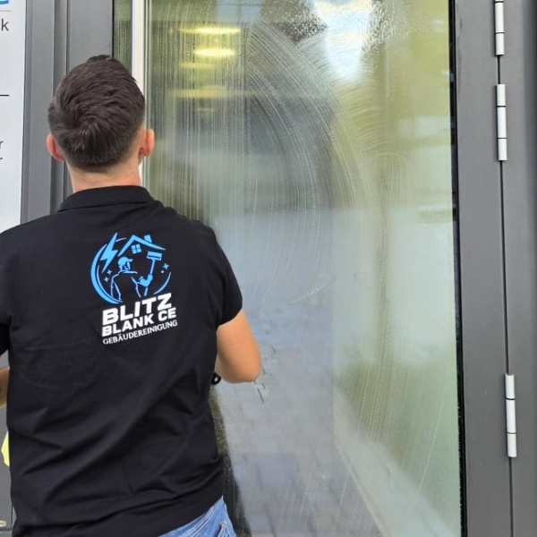 Mitarbeiter von Blitzblank reinigt eine Glastür von außen
