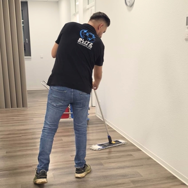 Mitarbeiter von Blitzblank wischt den Flur einer Praxis