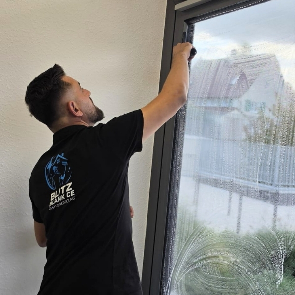 Mitarbeiter von Blitzblank reinigt ein Fenster mit dem Abzieher